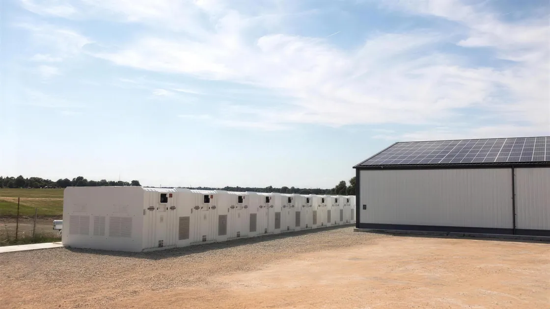 Batteriespeicher-Container neben einer Gewerbehalle mit Solardach