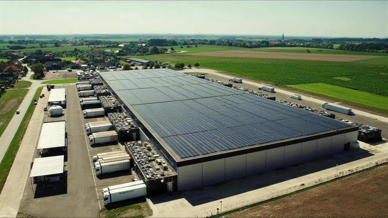 Luftaufnahme eines Logistikzentrums mit Solardach und Lkw an den Rampen