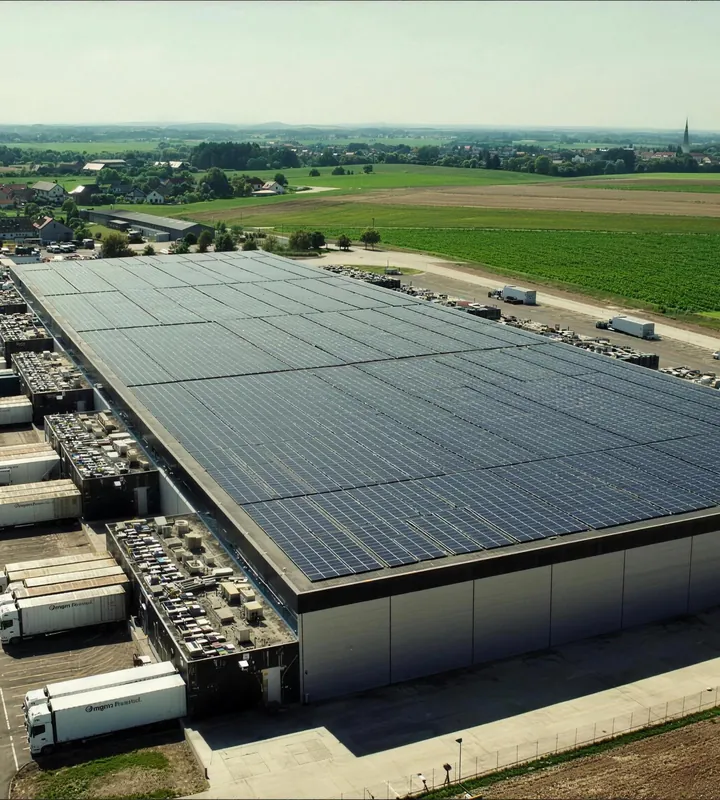 Luftaufnahme eines Logistikzentrums mit Solardach und Lkw an den Verladerampen